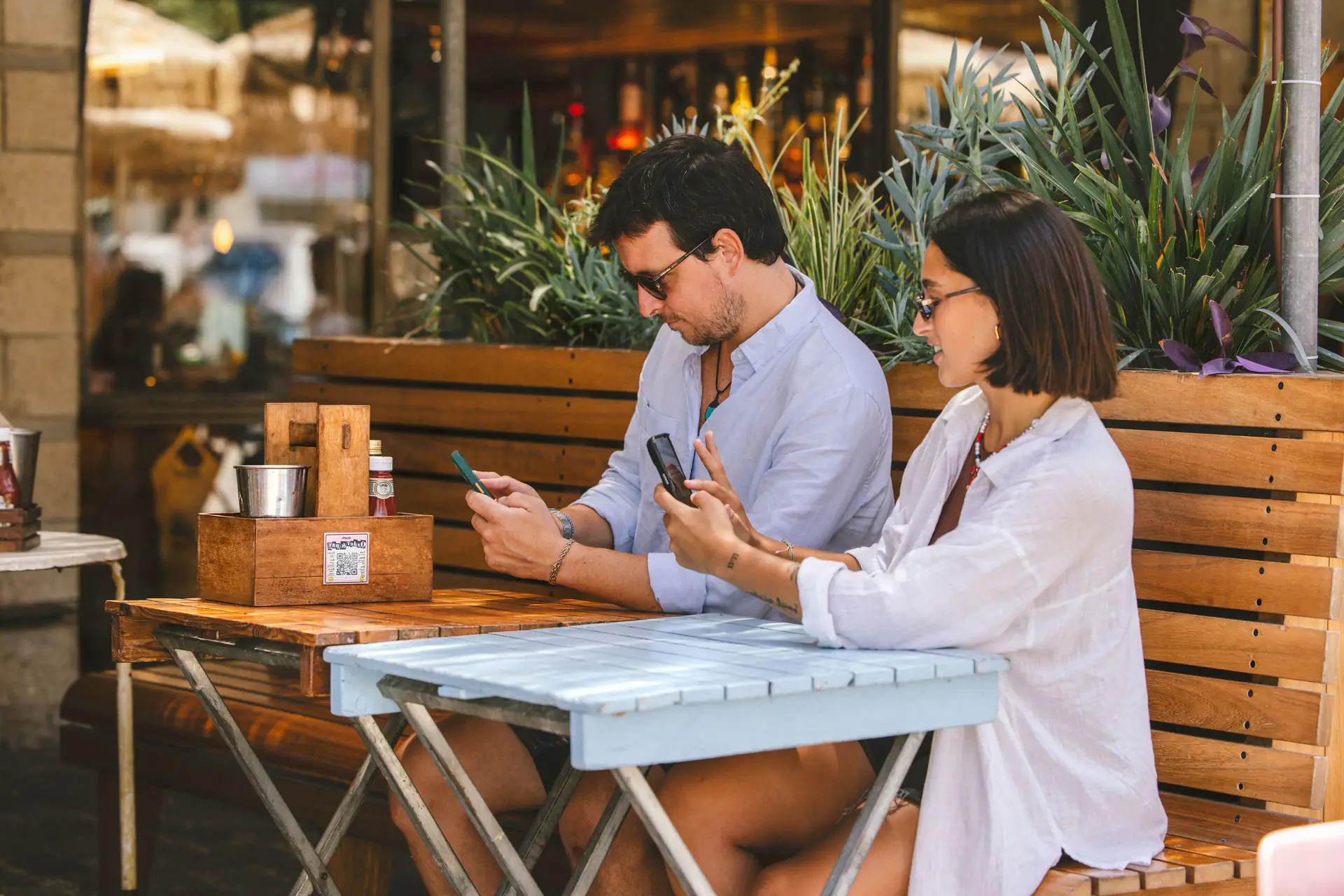 Dos clientes pagan su parte de la cuenta desde el móvil en una terraza